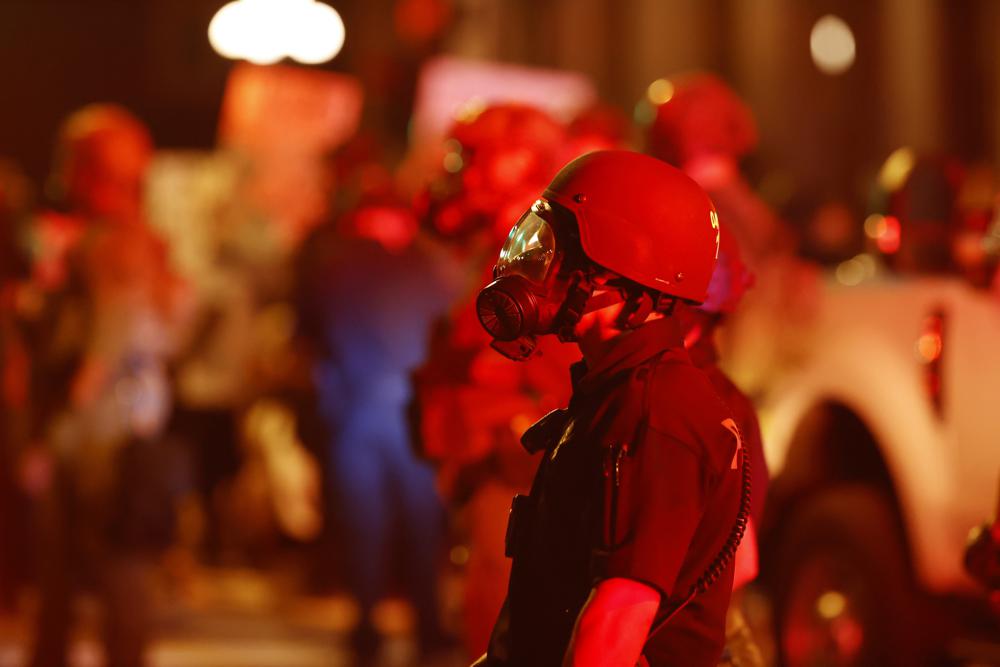 A Denver police officer wears a gas mask before tear gas and rubber bullets were used to disperse protesters outside the State Capitol over the death of George Floyd, May 28, 2020, in Denver.