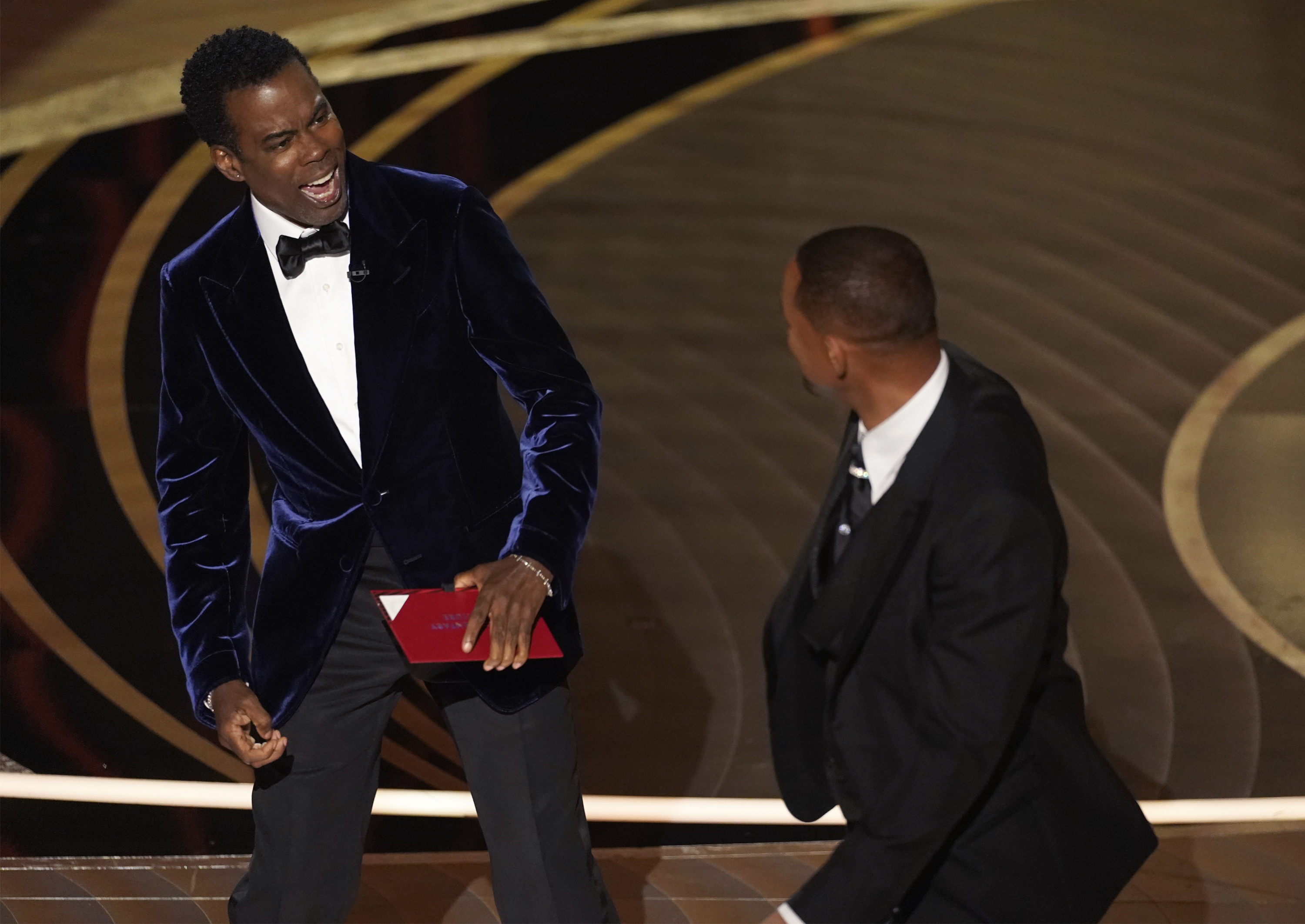 Presenter Chris Rock, left, reacts after being hit on stage by Will Smith while presenting the award for best documentary feature at the Oscars on Sunday, at the Dolby Theatre in Los Angeles. 