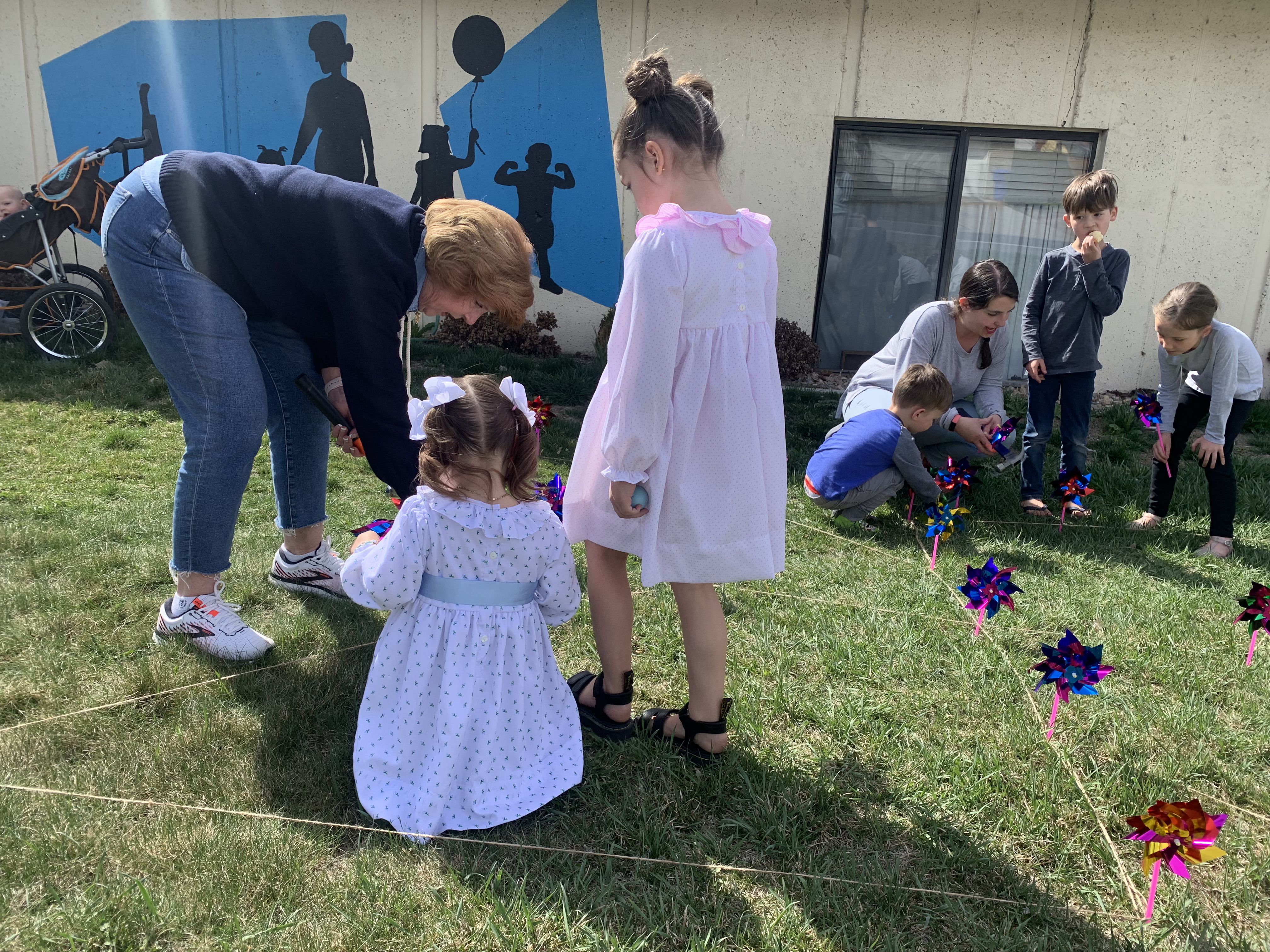 Kay Lindsay helps her great-granddaughters, August Roney and Bailey Clark, place a pinwheel outside Family Haven, 1255 N. 1200 West in Orem, on Friday. The pinwheels are part of the nonprofit organization's celebration of Family Strengthening Month and represent playfulness. 