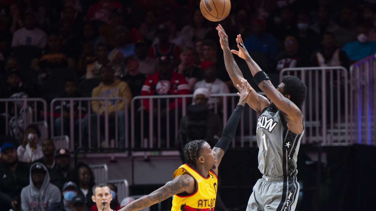 Brooklyn Nets guard Kyrie Irving (11) shoots a 3-point basket over Atlanta Hawks guard Delon Wright (0) during the first half of an NBA basketball game Saturday, April 2, 2022, in Atlanta.