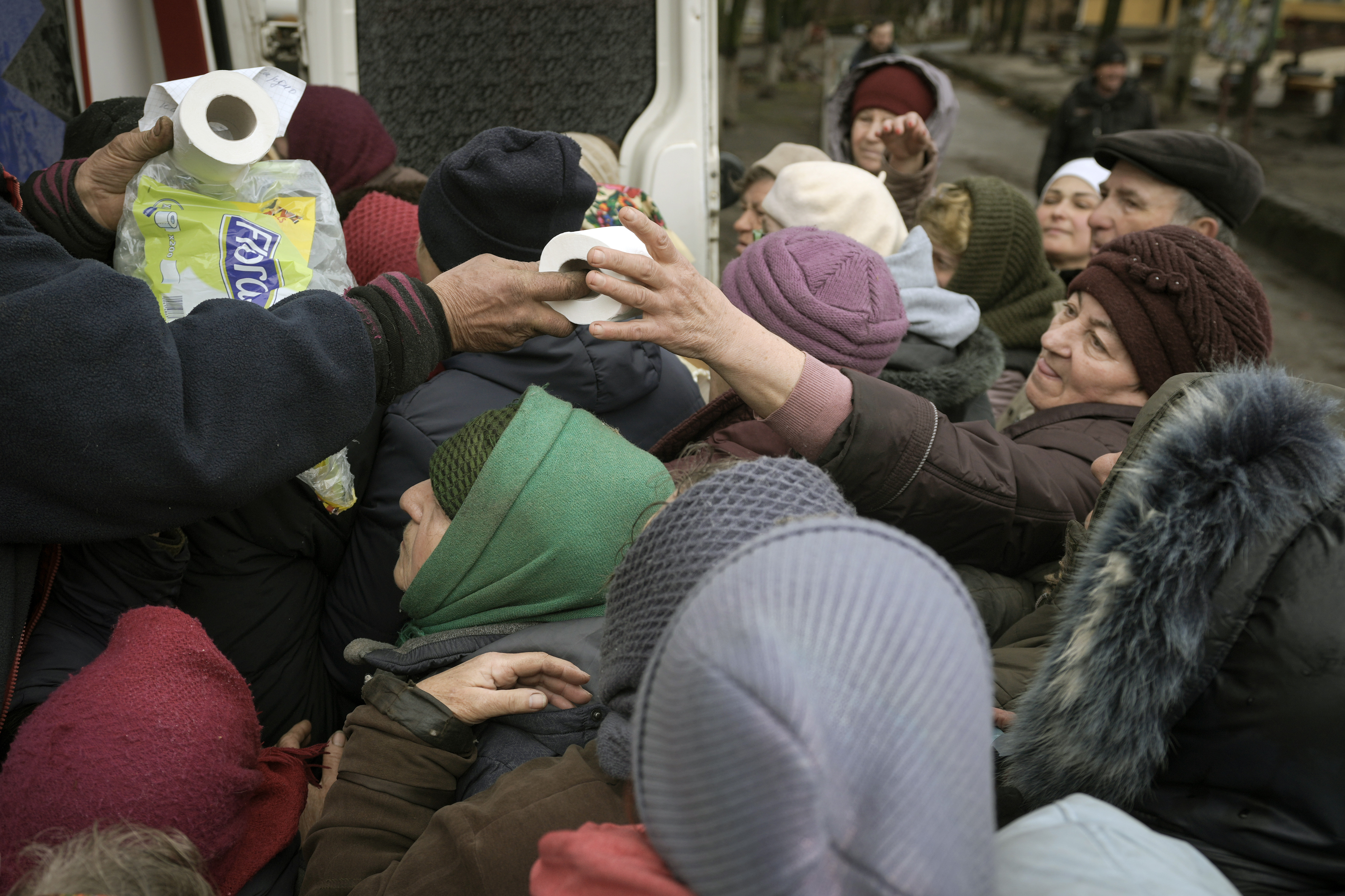 A man distributes toilet paper rolls as people wait for medicine and sanitary supplies handouts after a convoy of military and aid vehicles arrived in the formerly Russian-occupied Kyiv suburb of Bucha, Ukraine, Saturday.