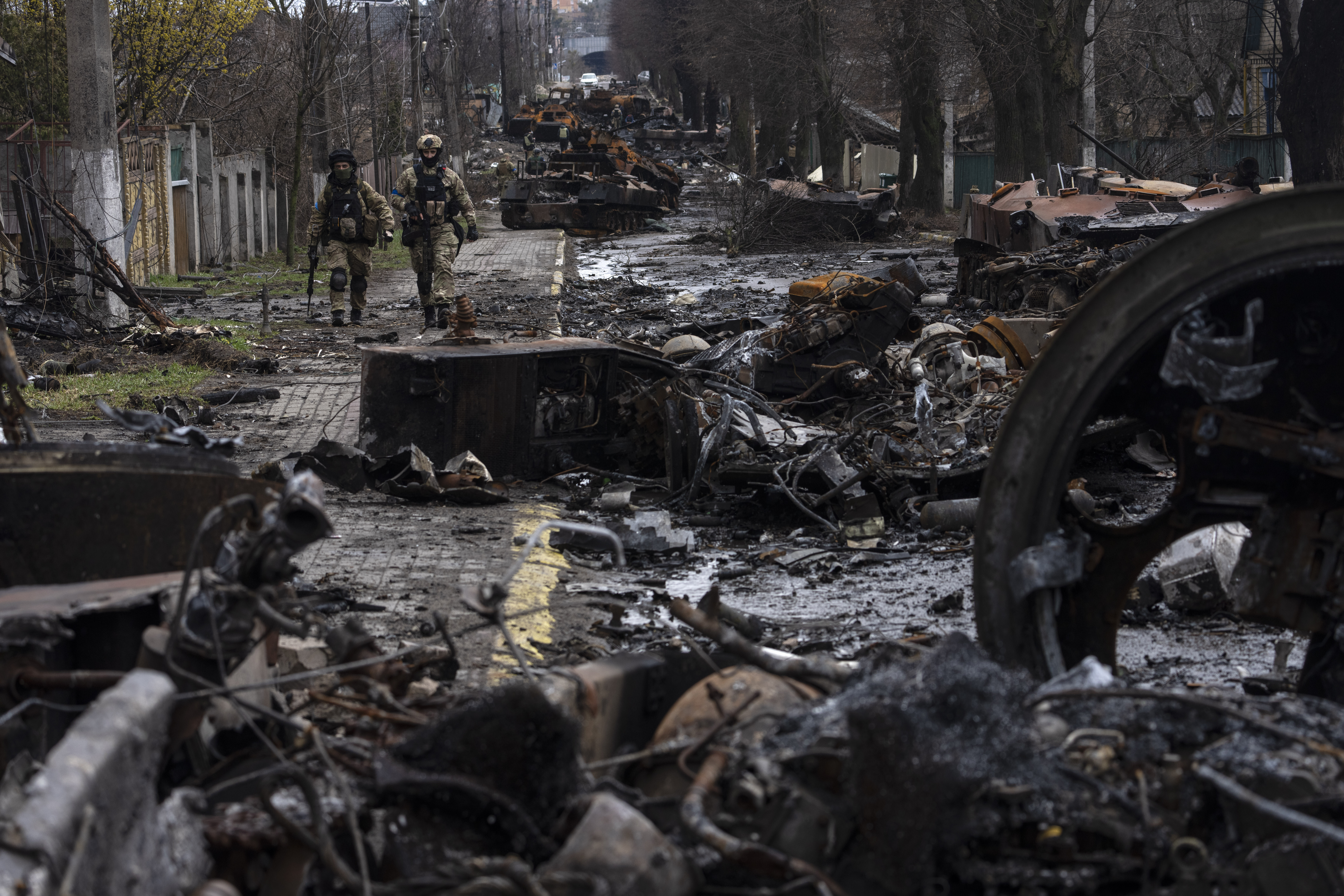 Soldiers walk amid destroyed Russian tanks in Bucha, in the outskirts of Kyiv, Ukraine, Sunday.