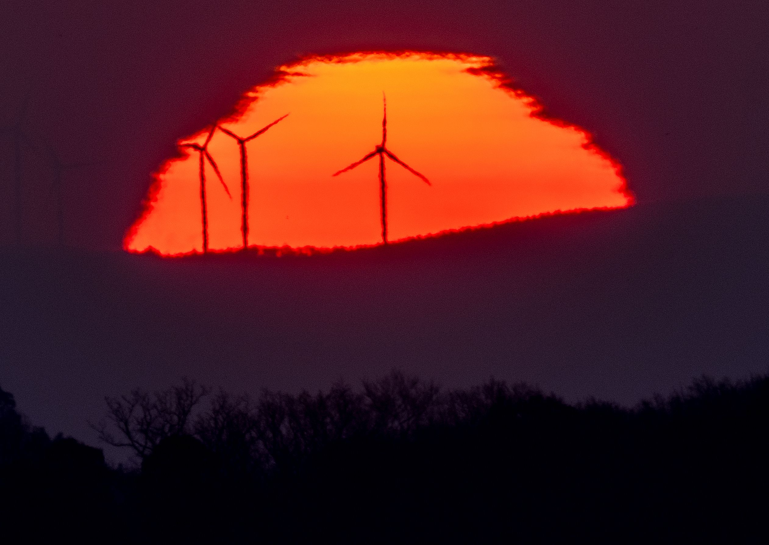 Wind turbines stand in front of the rising sun in Frankfurt, Germany, on Friday, March 11. The latest Intergovernmental Panel on Climate Change report warns that 2010-2019 average annual global greenhouse gas emissions were at their highest levels in human history and urgent action is needed.