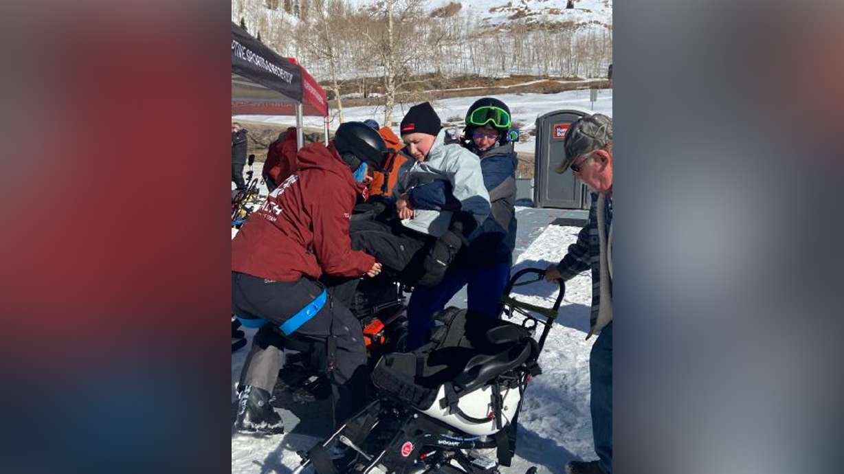 Travis Jensen lifts his son Terell Jensen into the TetraSki at Powder Mountain. Terell became a C5 quadriplegic after a sledding accident in 2019.