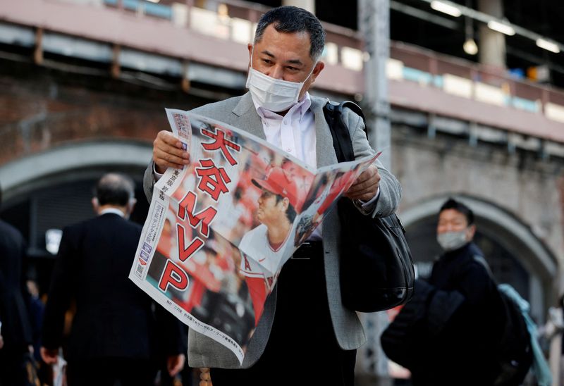 FILE PHOTO: A man reads an extra edition of a newspaper, reporting Japan's Shohei Ohtani of the Los Angeles Angels was named Most Valuable Player of Major League Baseball's American League, in Tokyo, Japan November 19, 2021.