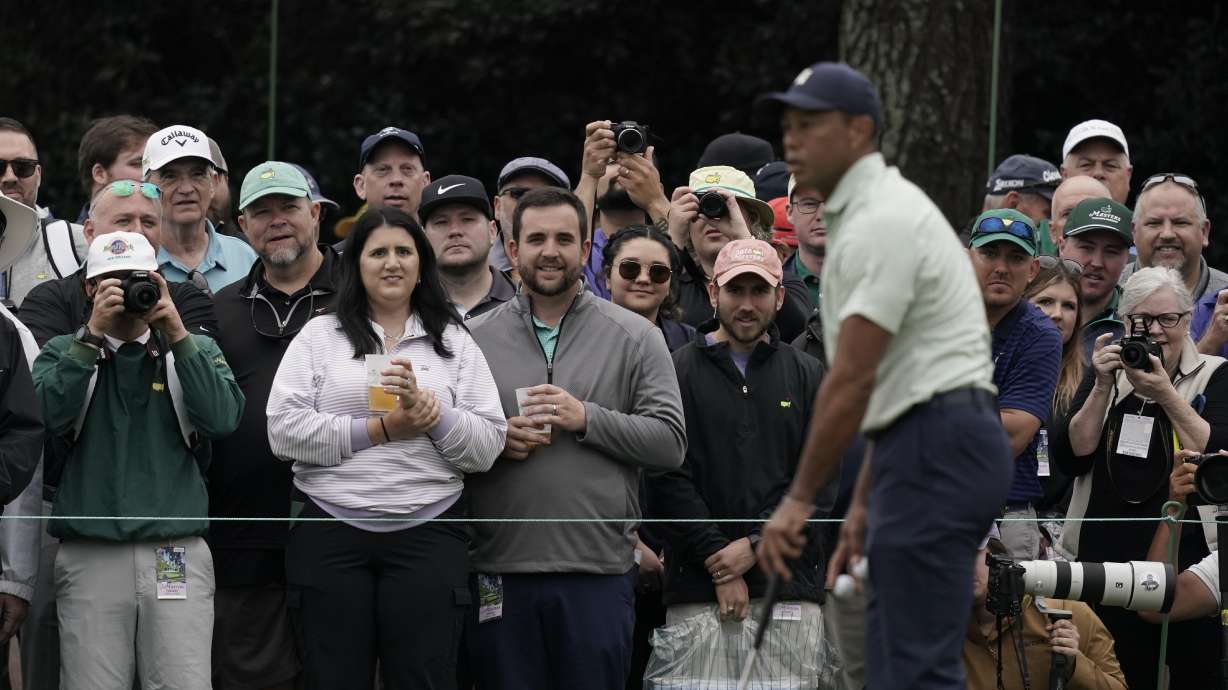 Spectators watch Tiger Woods on the driving range during a practice round for the Masters golf tournament on Tuesday, April 5, 2022, in Augusta, Ga.