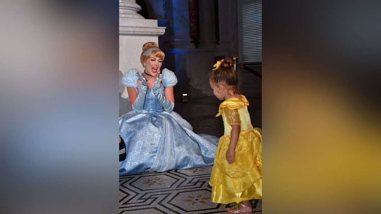 Costumed Cinderella greets a young guest at an event marking the inclusion of Disney's "Cinderella" into the National Film Registry on its 70th anniversary, June 20, 2019, at the Library of Congress in Washington. Costumed characters will soon be able to hug again.