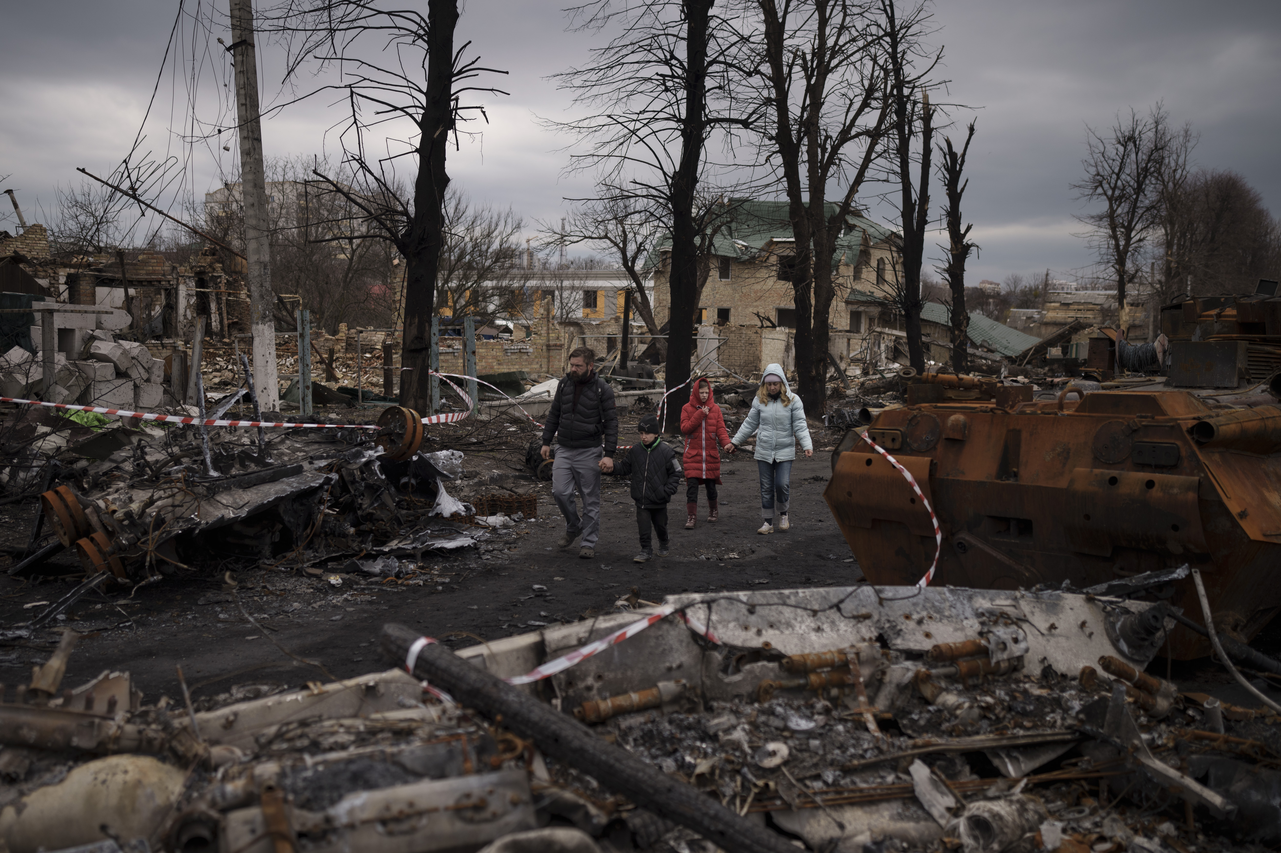 A family walks amid destroyed Russian tanks in Bucha, on the outskirts of Kyiv, Ukraine, Wednesday.