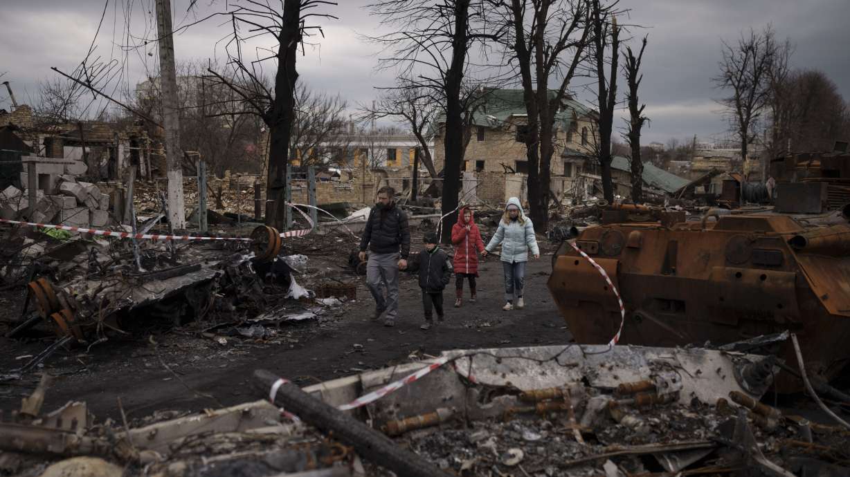 A family walks amid destroyed Russian tanks in Bucha, on the outskirts of Kyiv, Ukraine, Wednesday.