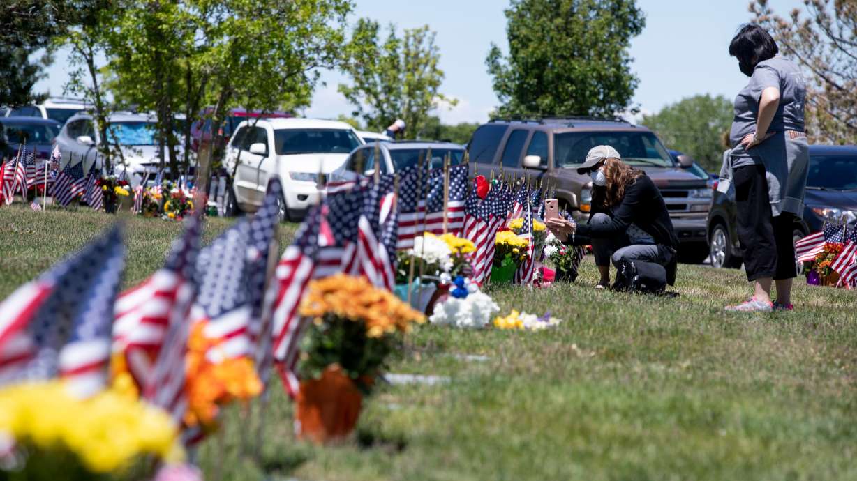 Christina Deckard photographs her father’s gravesite while her friend Jenna Seeley accompanies her at Utah Veterans Cemetery and Memorial Park in Bluffdale on Memorial Day, Monday, May 25.