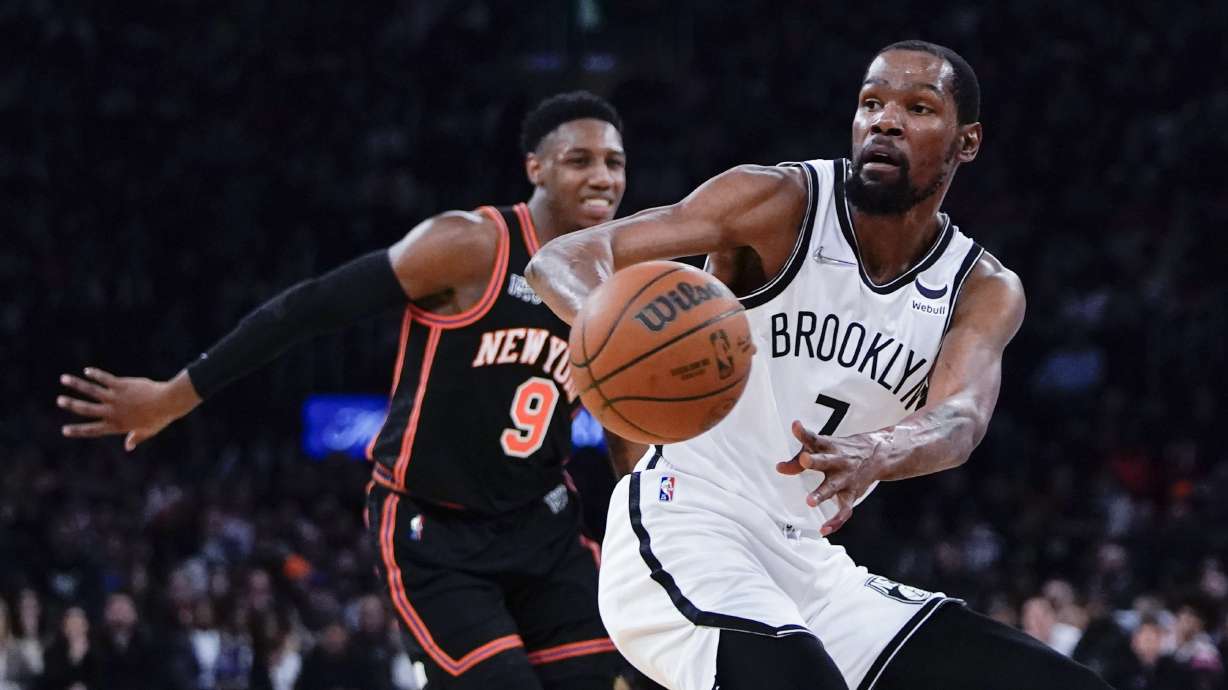 Brooklyn Nets' Kevin Durant (7) passes the ball away from New York Knicks' RJ Barrett (9) during the first half of an NBA basketball game Wednesday, April 6, 2022, in New York.