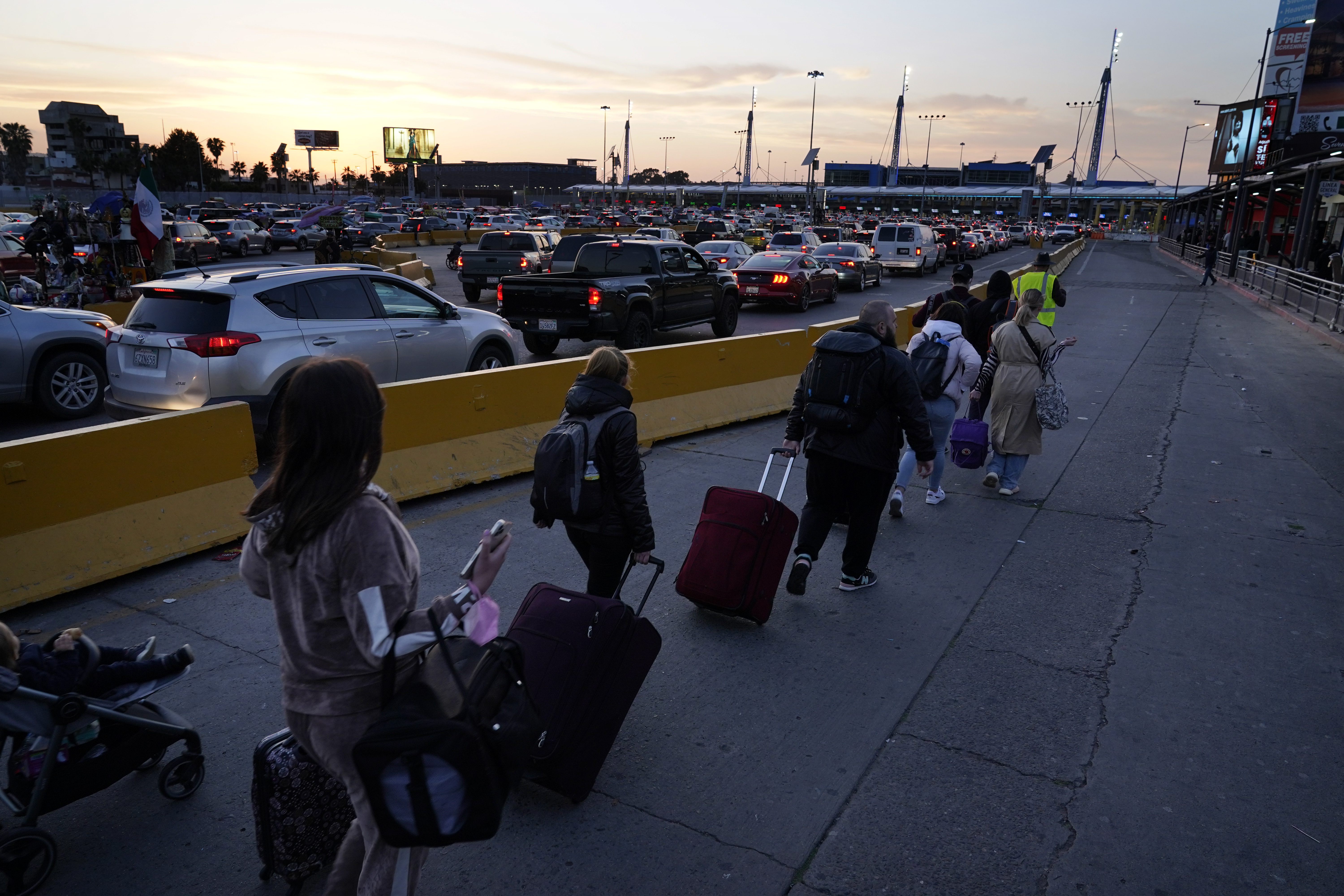 Ukrainian refugees follow a volunteer closer to the San Ysidro Port of Entry as they prepare to cross the border Monday, in Tijuana, Mexico. About 200 to 300 Ukrainians were being admitted daily at the San Ysidro crossing this week, with hundreds more arriving in Tijuana, according to volunteers who manage the waiting list. There were 973 families or single adults waiting on Tuesday.