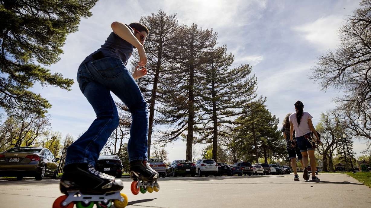 A rollerblader passes a pair of people walking on the sidewalk pathway at Liberty Park in Salt Lake City on April 30, 2021. Salt Lake City Department of Public Lands has finalized its 20-year master plan for the future of the city's parks and public lands.