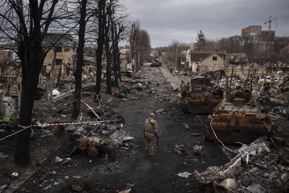 A Ukrainian serviceman walks amid destroyed Russian tanks in Bucha, on the outskirts of Kyiv, Ukraine, Wednesday. Russian troops left behind crushed buildings, streets littered with destroyed cars and residents in dire need of food and other aid in a northern Ukrainian city, giving fuel to Kyiv’s calls Thursday for more Western support.