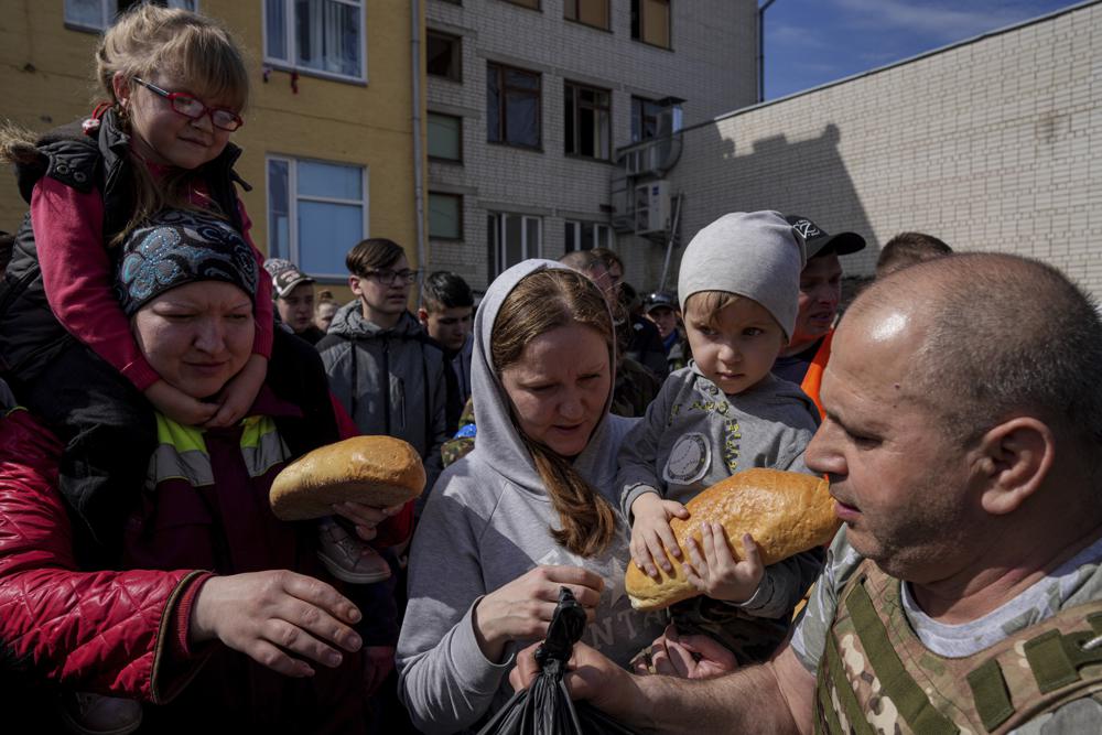 A volunteer, right, distributes humanitarian aid in a yard of a school in Chernihiv, Ukraine, Thursday.