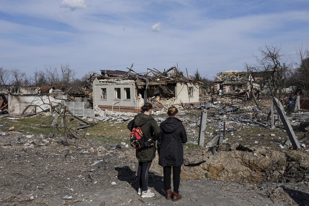 Women look at houses damaged by shelling in Chernihiv, Ukraine, Thursday. Ukraine is telling residents of its industrial heartland to leave while they still can after Russian forces withdrew from the shattered outskirts of Kyiv to regroup for an offensive in the country's east.