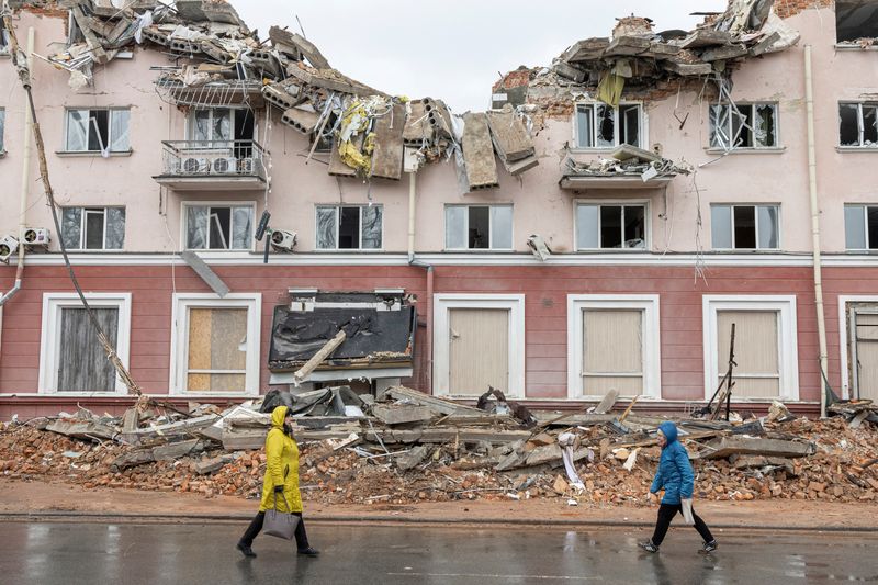 Women walk along a street in front of the destroyed Hotel Ukraine, as Russia's invasion of Ukraine continues, in Chernihiv, Ukraine, Wednesday.