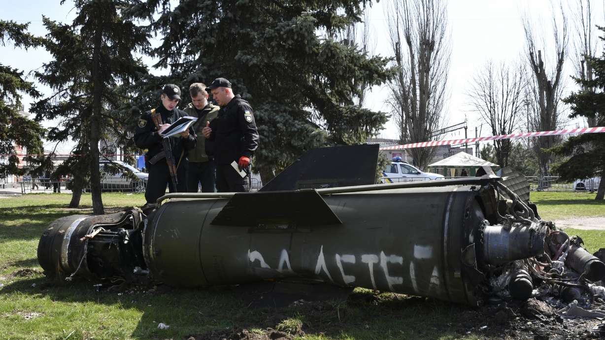 Ukrainian servicemen stand next to a fragment of a Tochka-U missile with a writing in Russian "For children," on a grass after Russian shelling at the railway station in Kramatorsk, Ukraine, on Friday.