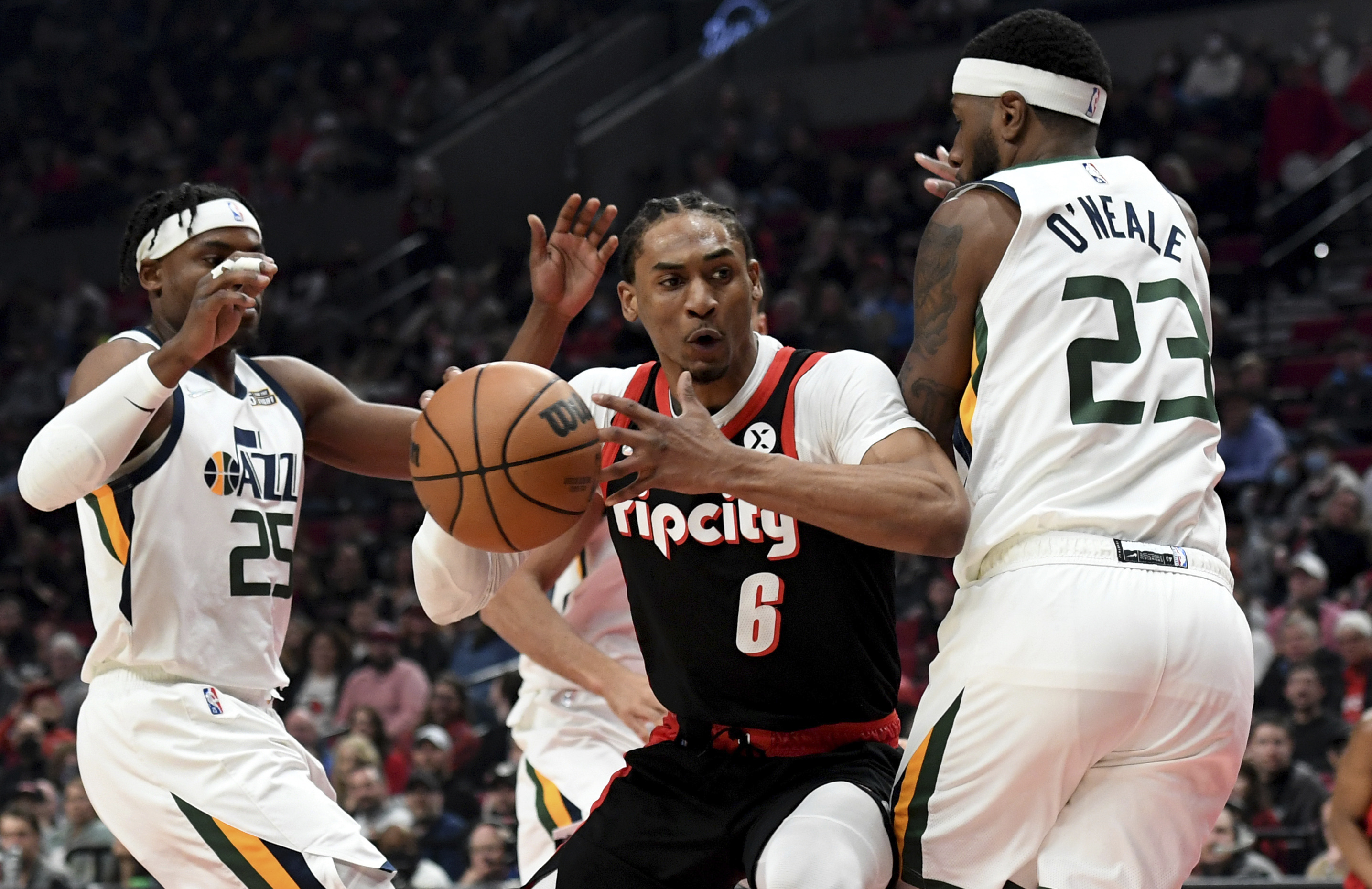 Portland Trail Blazers guard Keon Johnson, center, drive to the basket on Utah Jazz forward Danuel House Jr., left, and forward Royce O'Neale, right, during the first half of an NBA basketball game in Portland, Ore., Sunday.