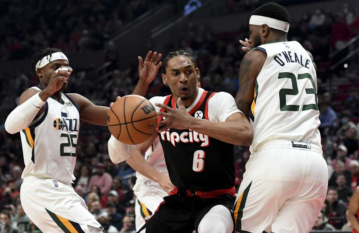 Portland Trail Blazers guard Keon Johnson, center, drive to the basket on Utah Jazz forward Danuel House Jr., left, and forward Royce O'Neale, right, during the first half of an NBA basketball game in Portland, Ore., Sunday.