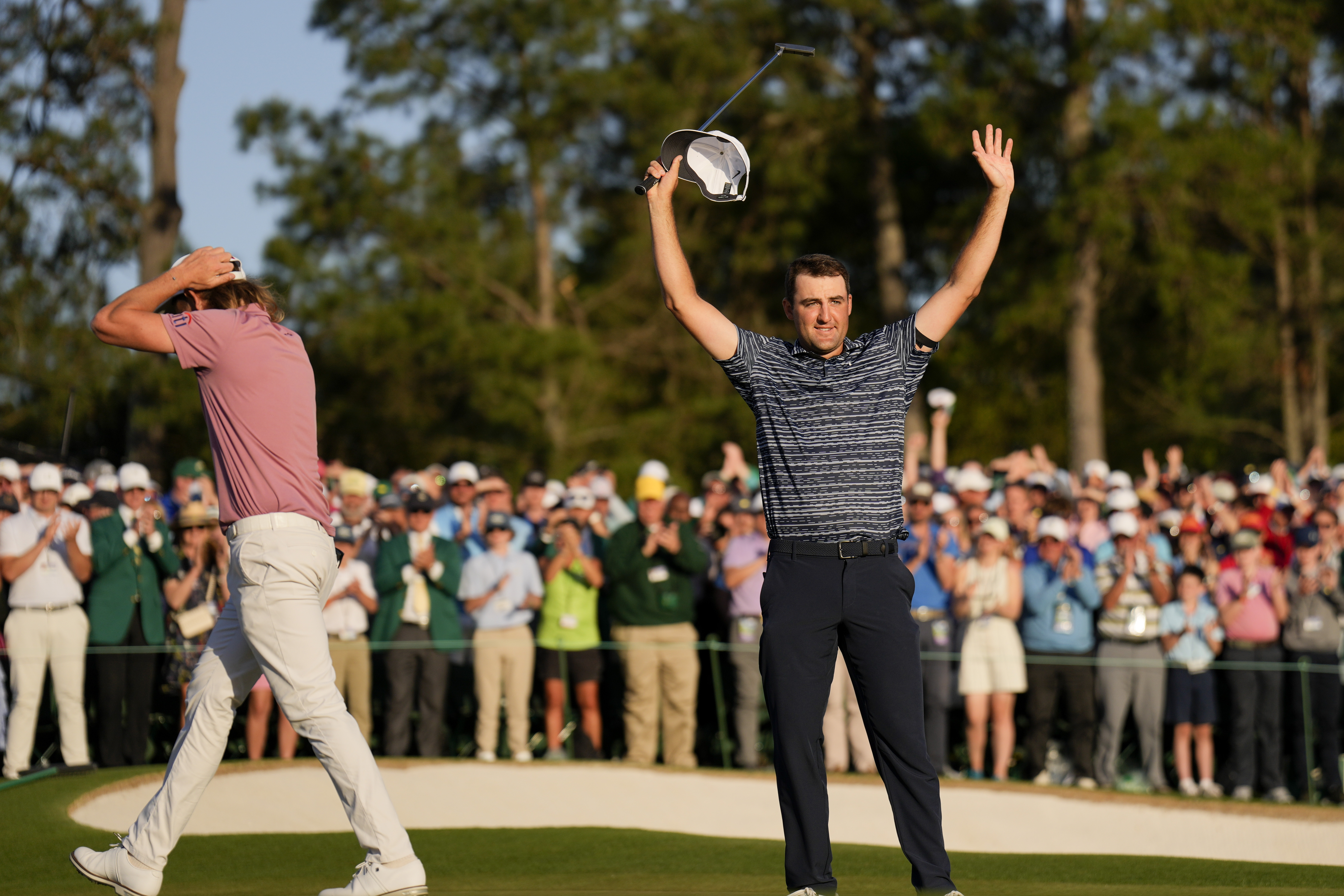 Cameron Smith, of Australia, walks past as Scottie Scheffler celebrates after winning the 86th Masters golf tournament on Sunday, April 10, 2022, in Augusta, Ga. 