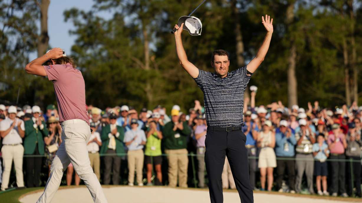 Cameron Smith, of Australia, walks past as Scottie Scheffler celebrates after winning the 86th Masters golf tournament on Sunday, April 10, 2022, in Augusta, Ga.