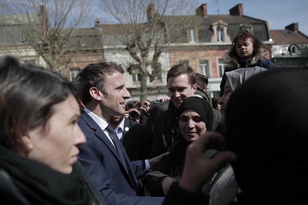 Current French President and centrist presidential candidate for reelection Emmanuel Macron meets residents in Denain, northern France, Monday. French President Emmanuel Macron may be ahead in the presidential race so far, but he warned his supporters that "nothing is done" and his runoff battle with far-right challenger Marine Le Pen will be a hard fight.