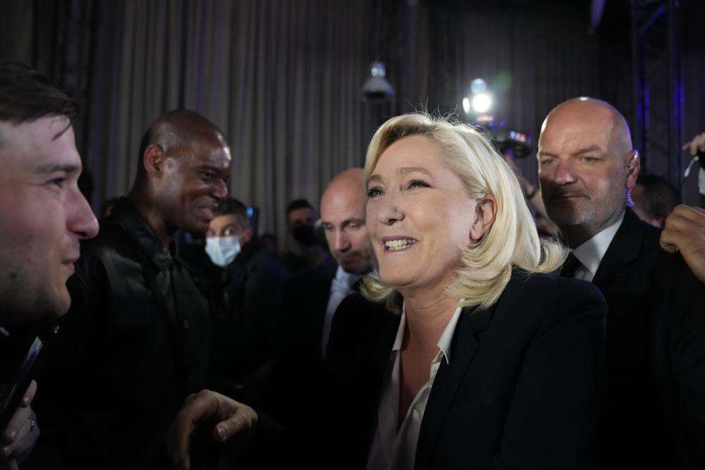 French far-right candidate Marine Le Pen shakes hands with supporters after delivering a speech at her election day headquarters in Paris, Sunday. French polling agency projections show incumbent French President Emmanuel Macron and far-right leader Marine Le Pen leading in the first round of France's presidential election Sunday.