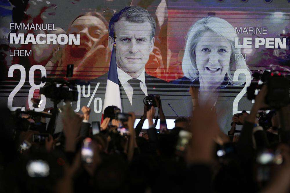 A screen shows French President Emmanuel Macron and centrist candidate for reelection and far-right candidate Marine Le Pen at her election day headquarters, in Paris, Sunday. French polling agency projections show incumbent French President Emmanuel Macron and far-right leader Marine Le Pen leading in the first round of France's presidential election Sunday.