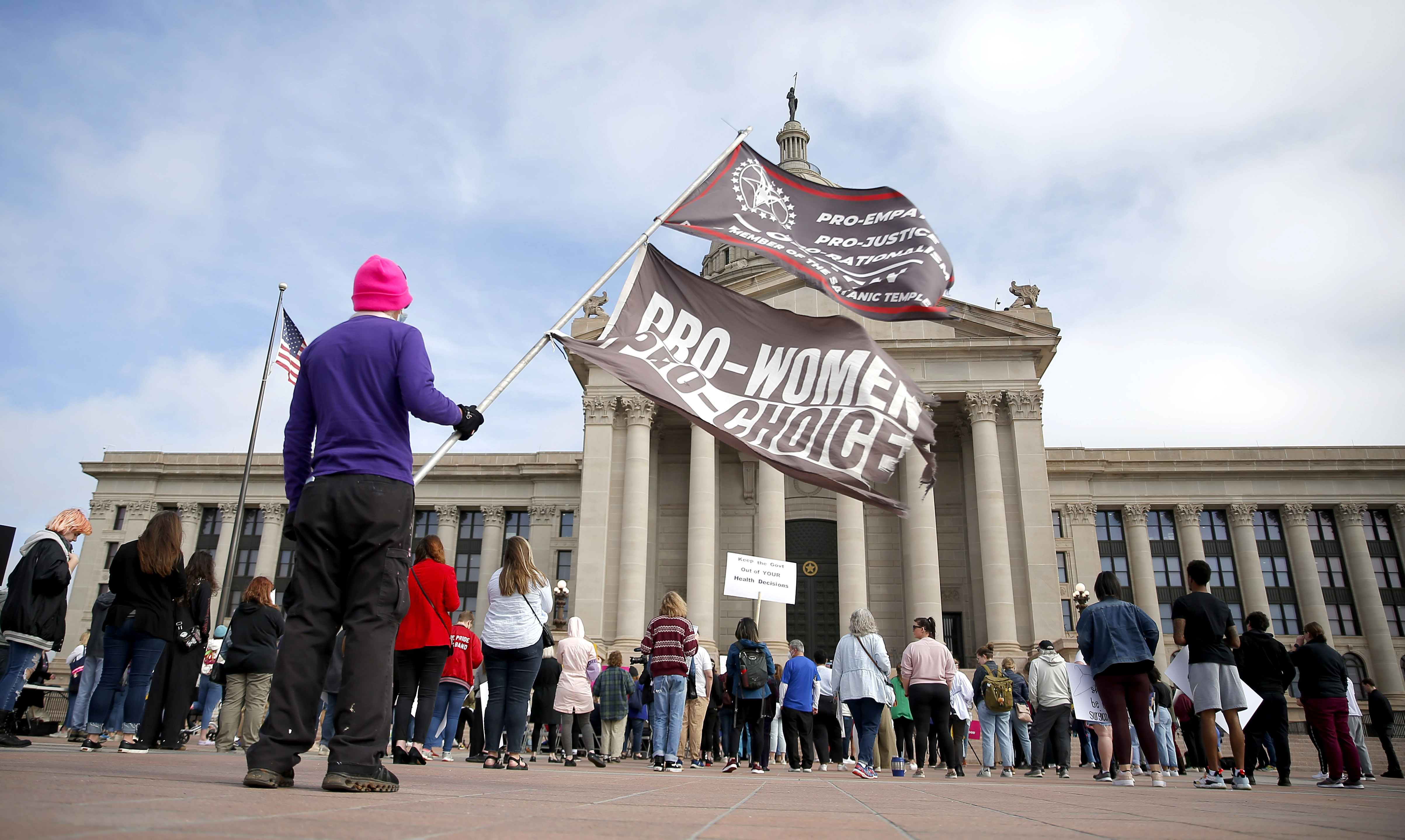 A person holds flags during the Bans Off Oklahoma Rally on the steps of the Oklahoma state Capitol in Oklahoma City, April 5. Oklahoma Gov. Kevin Stitt has signed into law a bill making it a felony to perform an abortion, punishable by up to 10 years in prison. Abortion rights advocates say the bill is clearly unconstitutional and is likely to face a legal challenge.