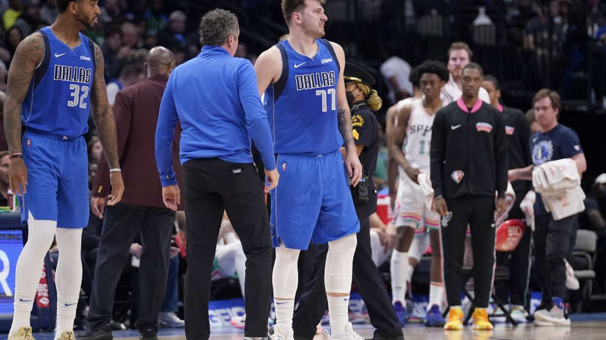 Dallas Mavericks' Marquese Chriss and a member of the staff check on guard Luka Doncic (77) who suffered an unknown lower leg injury in the second half of an NBA basketball game against the San Antonio Spurs, Sunday, April 10, 2022, in Dallas.
