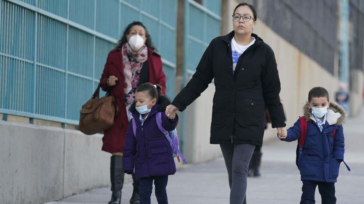 Children and their caregivers arrive for school in New York, Monday, March 7. The Biden administration will extend for two weeks the nationwide mask requirement for public transit as it monitors an uptick in COVID-19 cases.