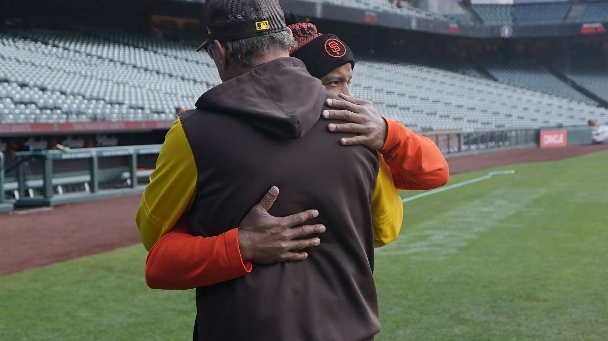 San Diego Padres third base coach Mike Shildt, back to camera, hugs San Francisco Giants first base coach Antoan Richardson after they spoke at a news conference before a baseball game in San Francisco, Wednesday, April 13, 2022.