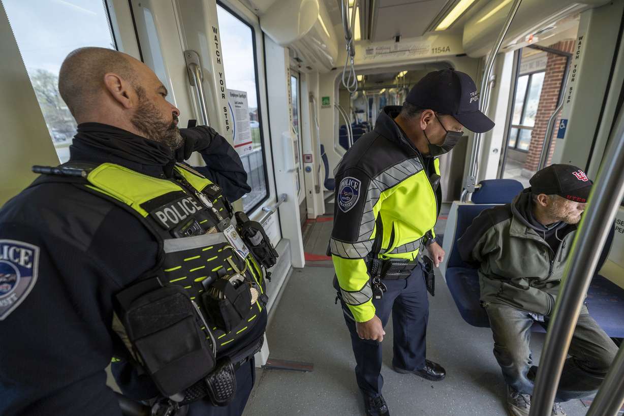 Utah Transit Authority police officers Phil Herrera and John Lobaido bring a man back to their office on a TRAX train after verifying that he had felonies as they checked tickets in the Murray area on Wednesday, April 13.