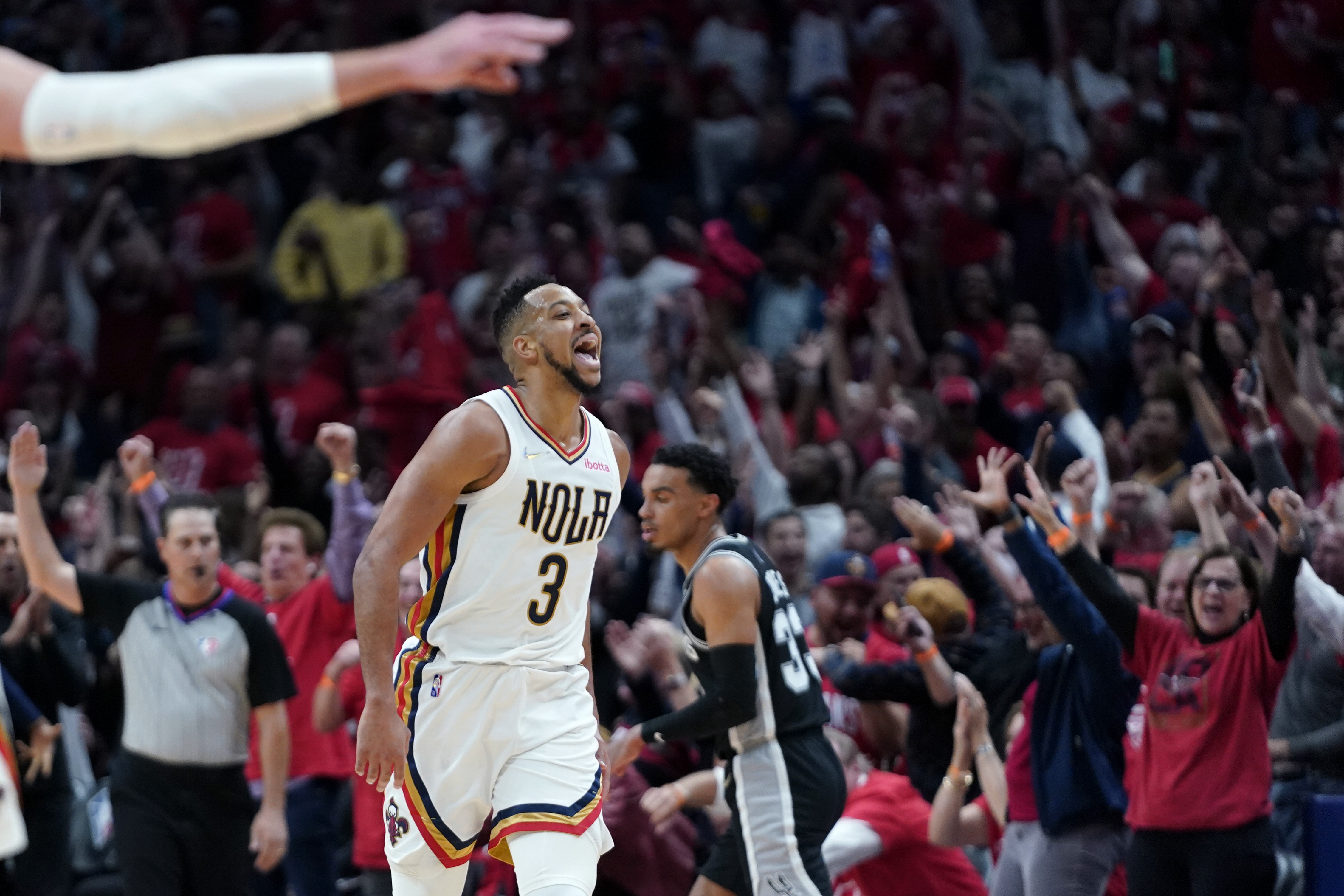 New Orleans Pelicans guard CJ McCollum (3) reacts with the crowd after scoring a 3-point basket in the first half of an NBA play-in basketball game against the San Antonio Spurs in New Orleans, Wednesday, April 13, 2022.