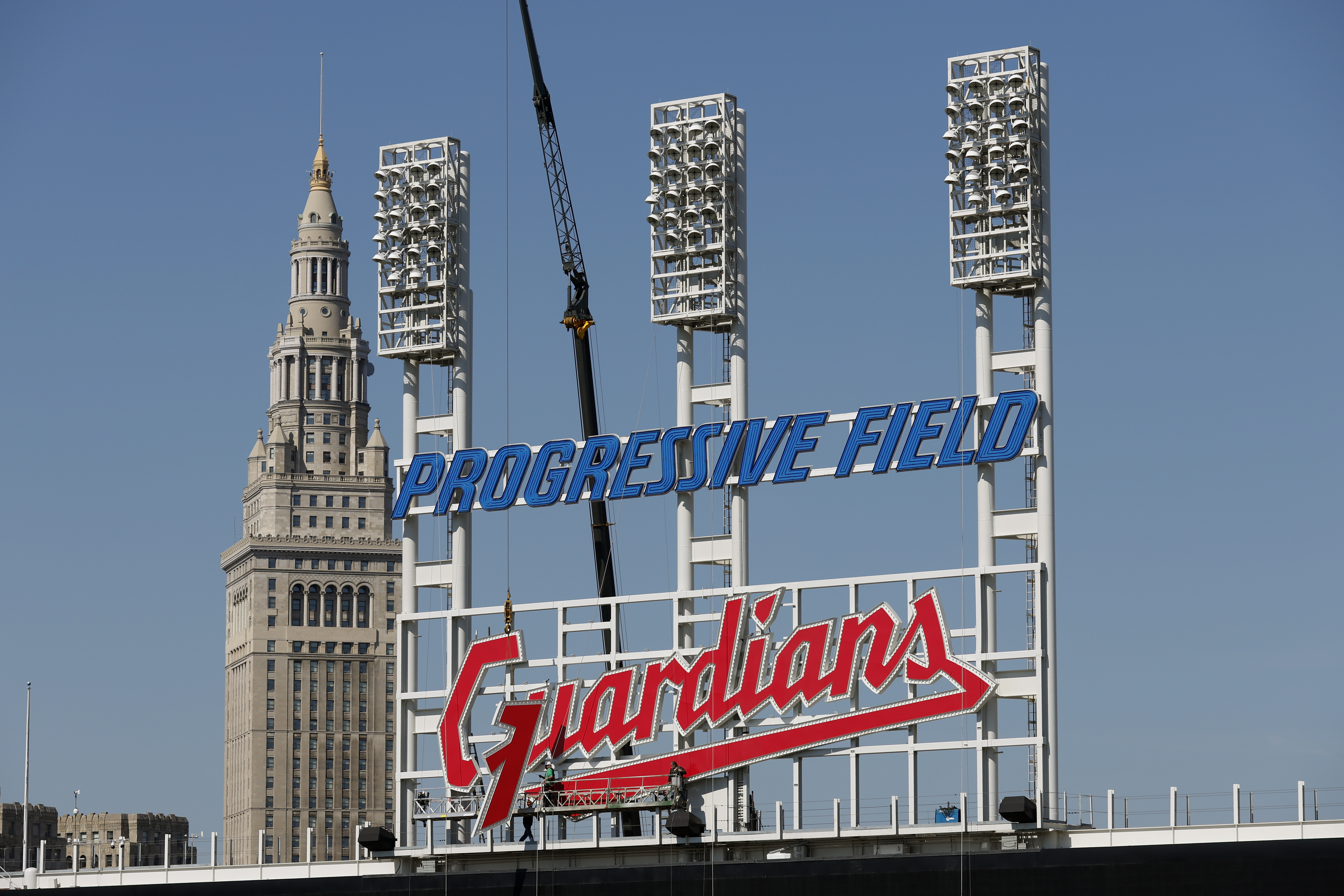FILE - Workers finish installing the Cleveland Guardians sign above the scoreboard at Progressive Field, Thursday, March 17, 2022, in Cleveland. On Friday, April 15, the renamed Guardians will play for the first time at Progressive Field, officially launching a new era for a team known as the Indians since 1915 before a long-debated and fan-dividing name change finally happened last year. 