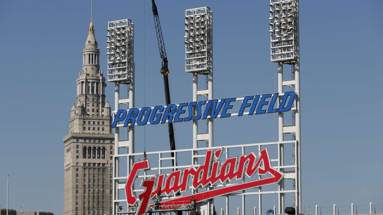 FILE - Workers finish installing the Cleveland Guardians sign above the scoreboard at Progressive Field, Thursday, March 17, 2022, in Cleveland. On Friday, April 15, the renamed Guardians will play for the first time at Progressive Field, officially launching a new era for a team known as the Indians since 1915 before a long-debated and fan-dividing name change finally happened last year.