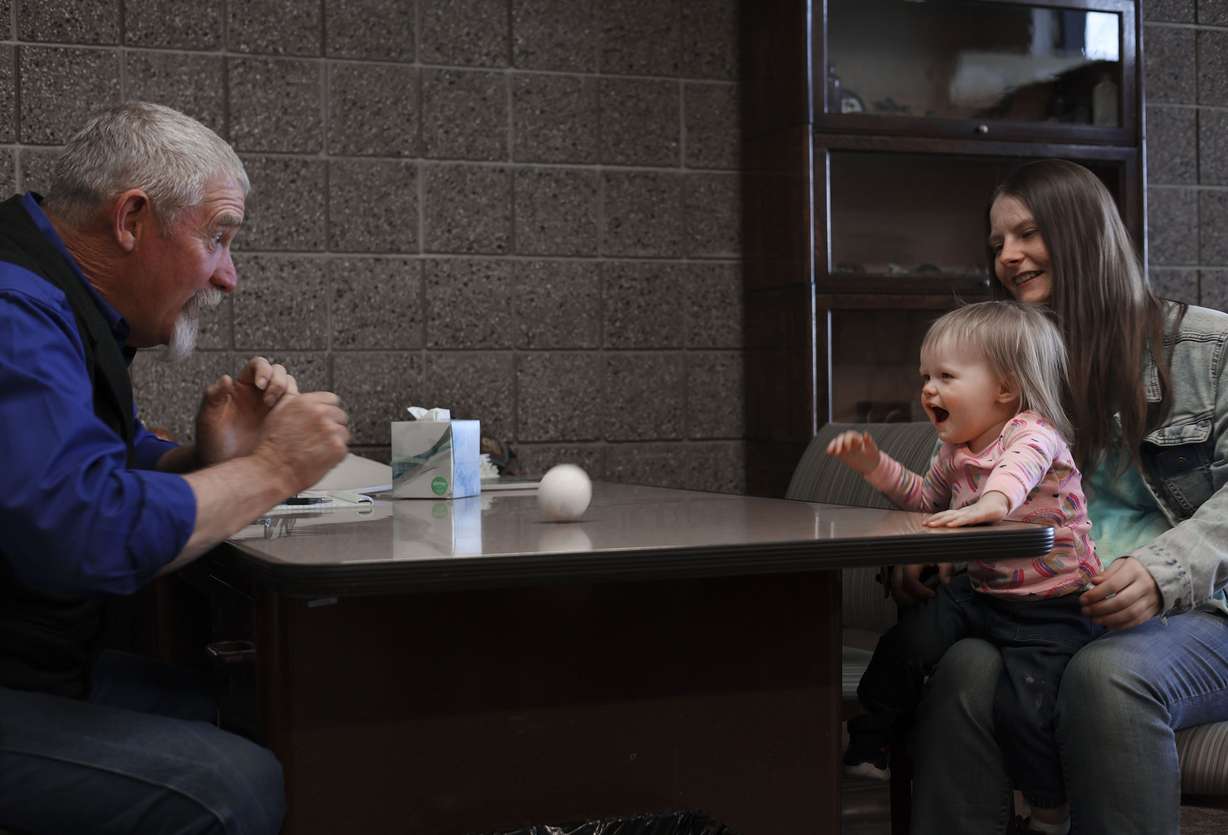 Carbon County Sheriff’s detective Wally Hendricks, left, plays ball with 1-year-old Scarlett Skiles and her mother, Josie Powell, at the detective’s office in Price on Sunday, April 3. Hendricks and Powell met three years ago after Powell was sexually assaulted. Hendricks remarked, “If you deal with us, you have us for life,”