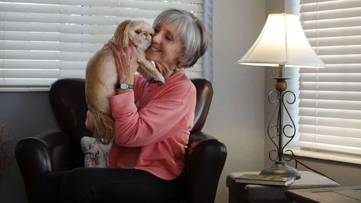 Carrie Smith plays with her friend’s dog Annie at her home in Washington on Thursday. She relies on Utah’s energy assistance program to help pay her home energy bills.