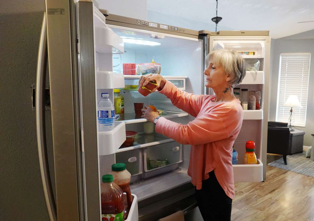 Carrie Smith gets food from the refrigerator at her home in Washington on Thursday. She relies on Utah’s energy assistance program to help pay her home energy bills.