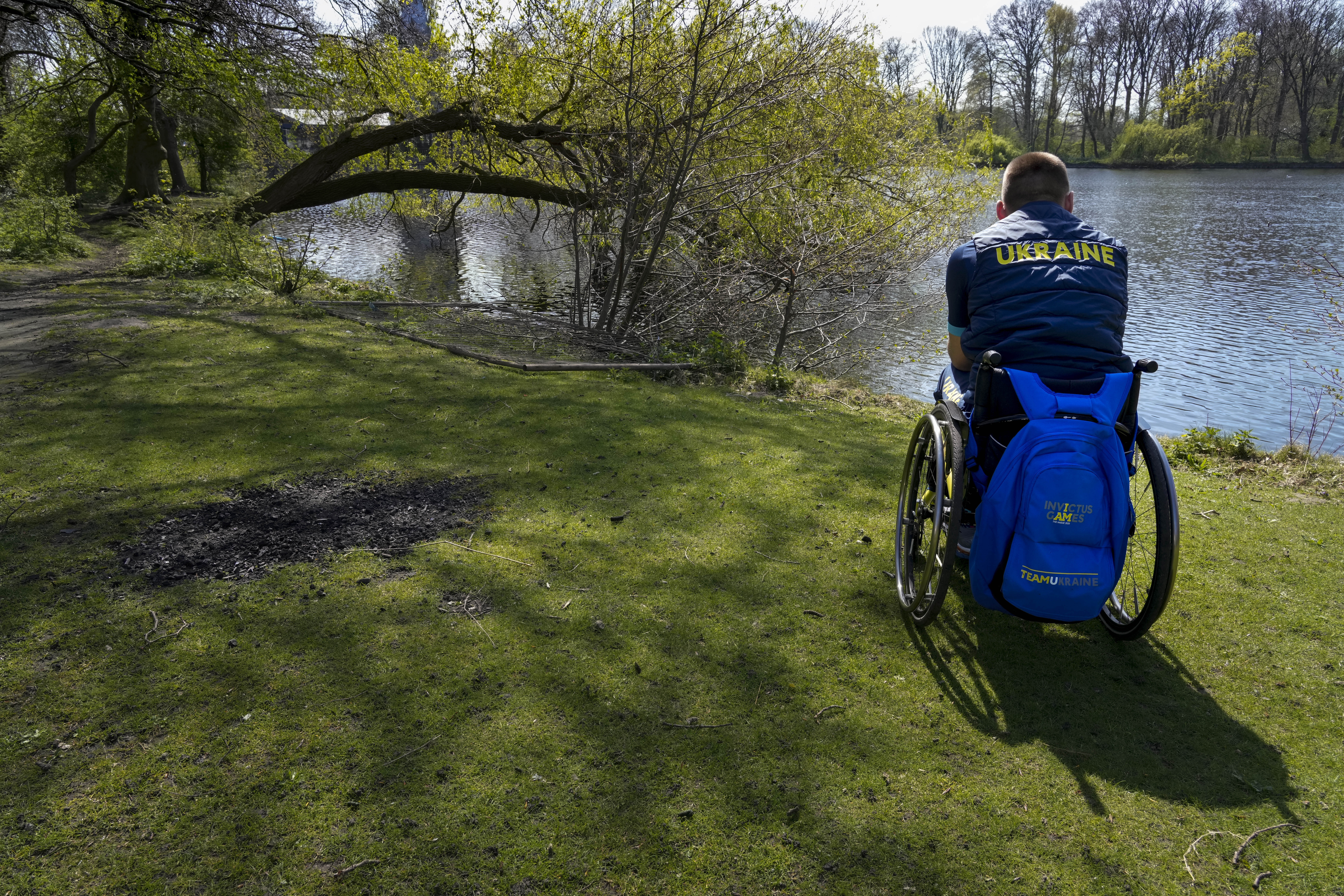 A member of Team Ukraine looks out over a lake at the Invictus Games venue in The Hague, Netherlands, Thursday, April 14, 2022. The week-long games for active servicemen and veterans who are ill, injured or wounded opens Saturday in this Dutch city that calls itself the global center of peace and justice. Those concepts seem a world away to the team of 19 athletes from Ukraine. 