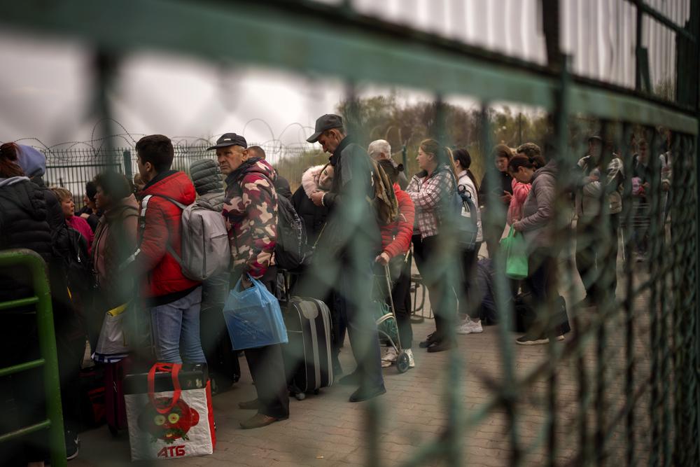 Ukrainians carrying their belongings line up to enter in Poland as they flee their country crossing the Medyka border, Friday.  More than 900 bodies of civilians were discovered in the Kyiv region following the withdrawal of Russian forces.
