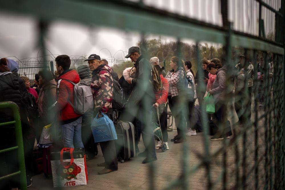 Ukrainians carrying their belongings line up to enter in Poland as they flee their country crossing the Medyka border, Friday. More than 900 bodies of civilians were discovered in the Kyiv region following the withdrawal of Russian forces.