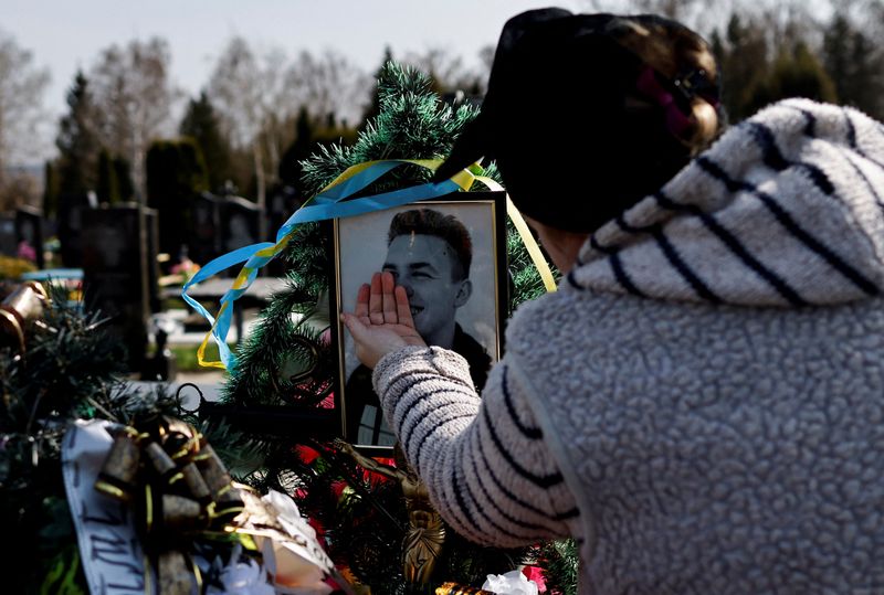 Natalia Evdokimova, 46, touches a photograph of her son Dmytro Evdokimov, 23, who was killed in a battlefield near Izium in Kharkiv region, as she mourns him beside his grave at the cemetery in Trostianets, Sumy region, Ukraine on Saturday.