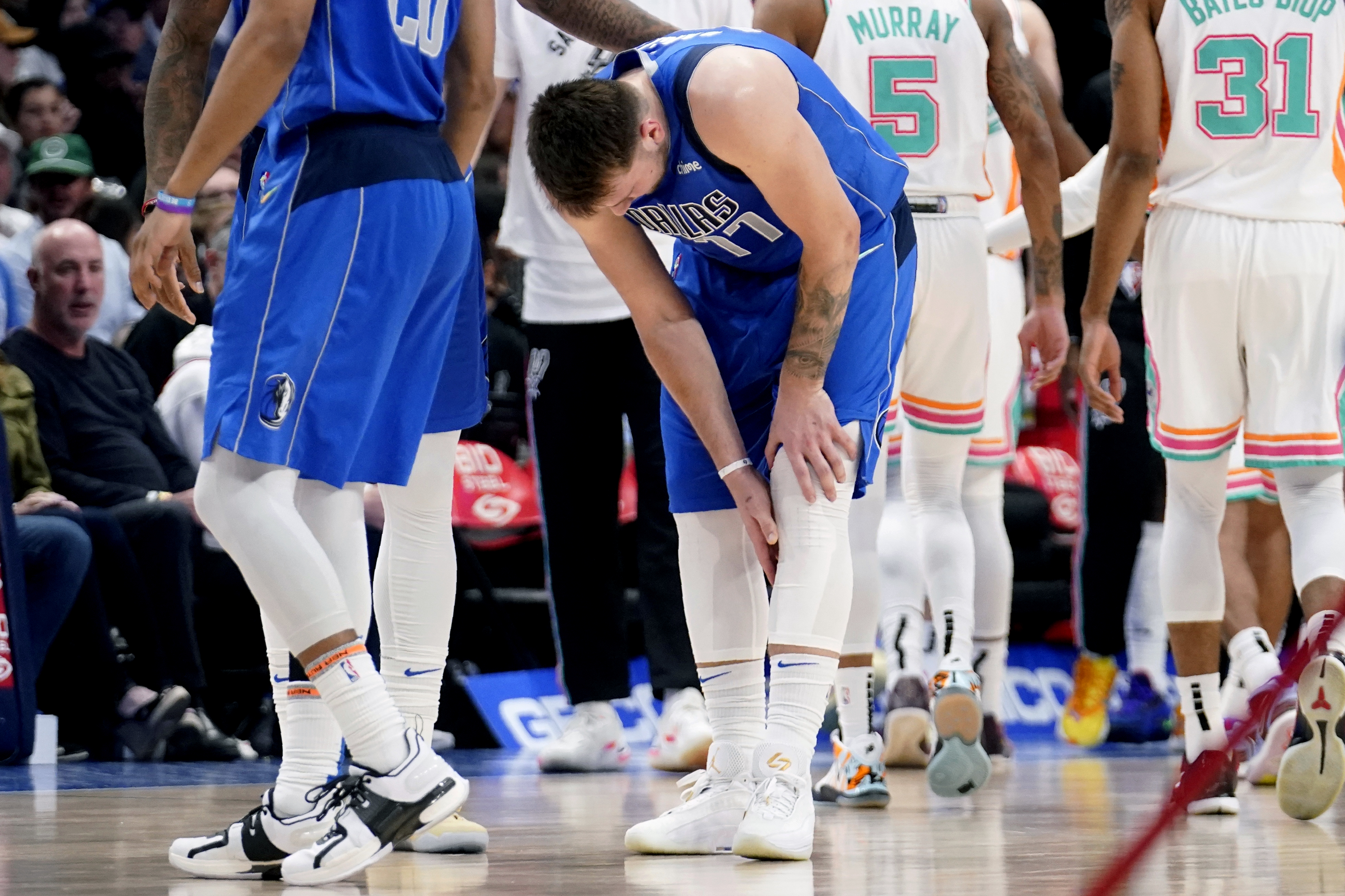 Dallas Mavericks' Luka Doncic (77) reaches for his lower leg after suffering an unknown lower leg injury in the second half of an NBA basketball game against the San Antonio Spurs, Sunday, April 10, 2022, in Dallas. 