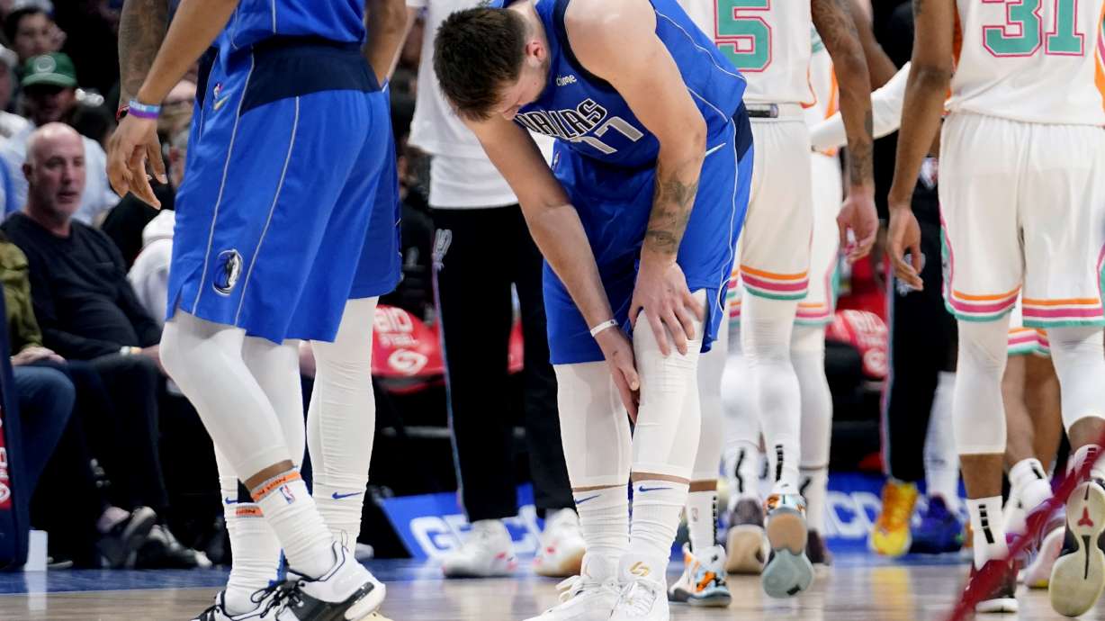 Dallas Mavericks' Luka Doncic (77) reaches for his lower leg after suffering an unknown lower leg injury in the second half of an NBA basketball game against the San Antonio Spurs, Sunday, April 10, 2022, in Dallas.