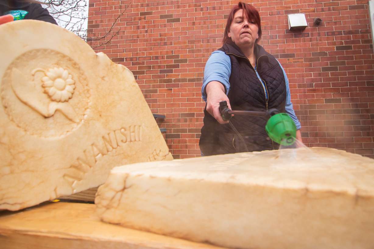 Amy Barry, cemeteries program manager for the Utah Division of State History, cleans K. Kawanishi's tombstone Saturday morning. Kawanishi is buried in a remote part of Grand County.