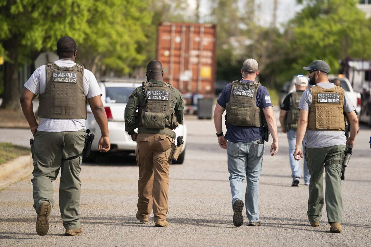Members of the U.S. Marshals fugitive task force walk down a street near Columbiana Centre mall in Columbia, S.C., following a shooting, Saturday.