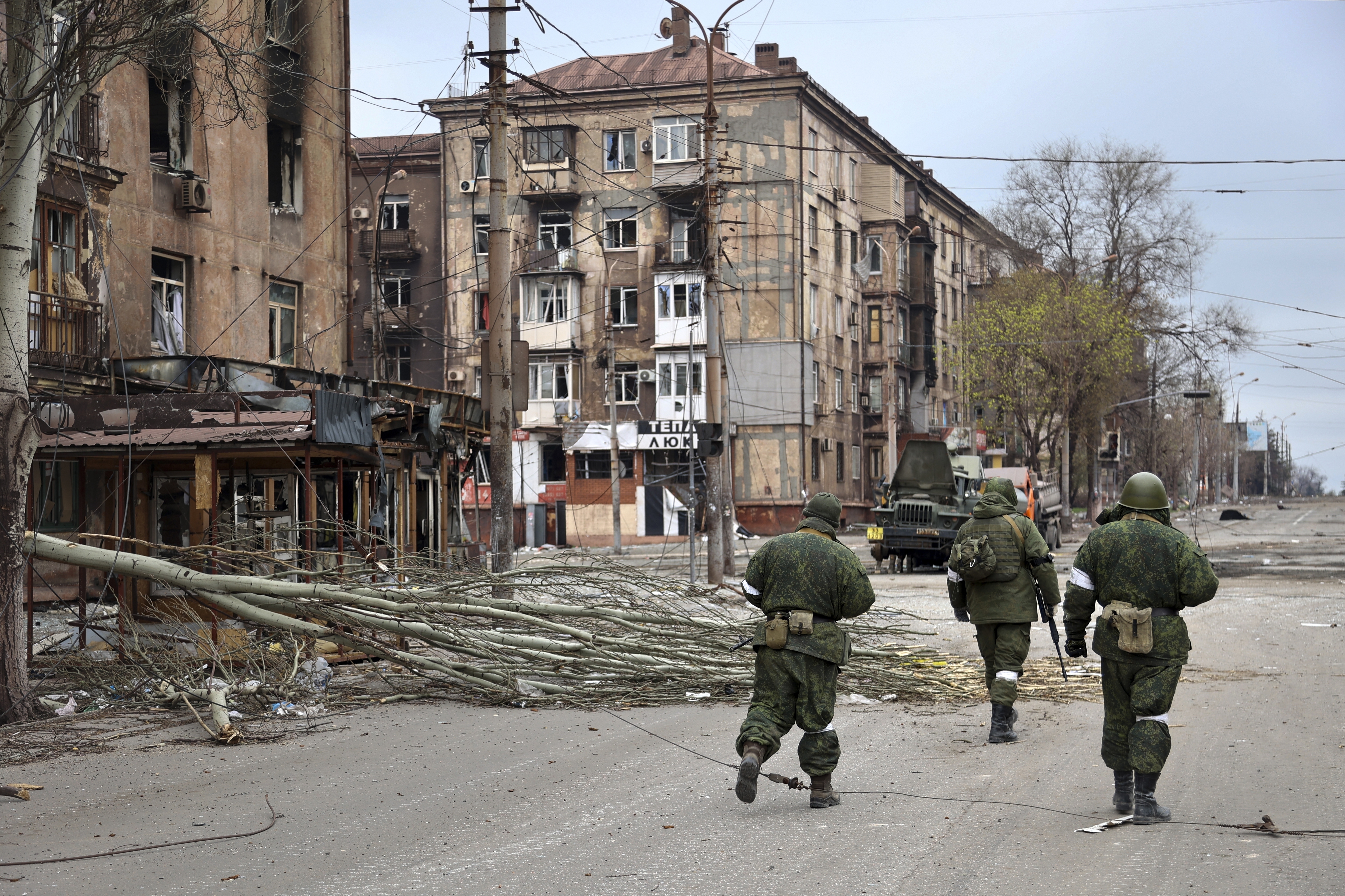 Servicemen of Donetsk People's Republic militia walk past damaged apartment buildings near the Illich Iron & Steel Works Metallurgical Plant, the second largest metallurgical enterprise in Ukraine, in an area controlled by Russian-backed separatist forces in Mariupol, Ukraine, on Saturday. Mariupol, a strategic port on the Sea of Azov, has been besieged by Russian troops and forces from self-proclaimed separatist areas in eastern Ukraine for more than six weeks.