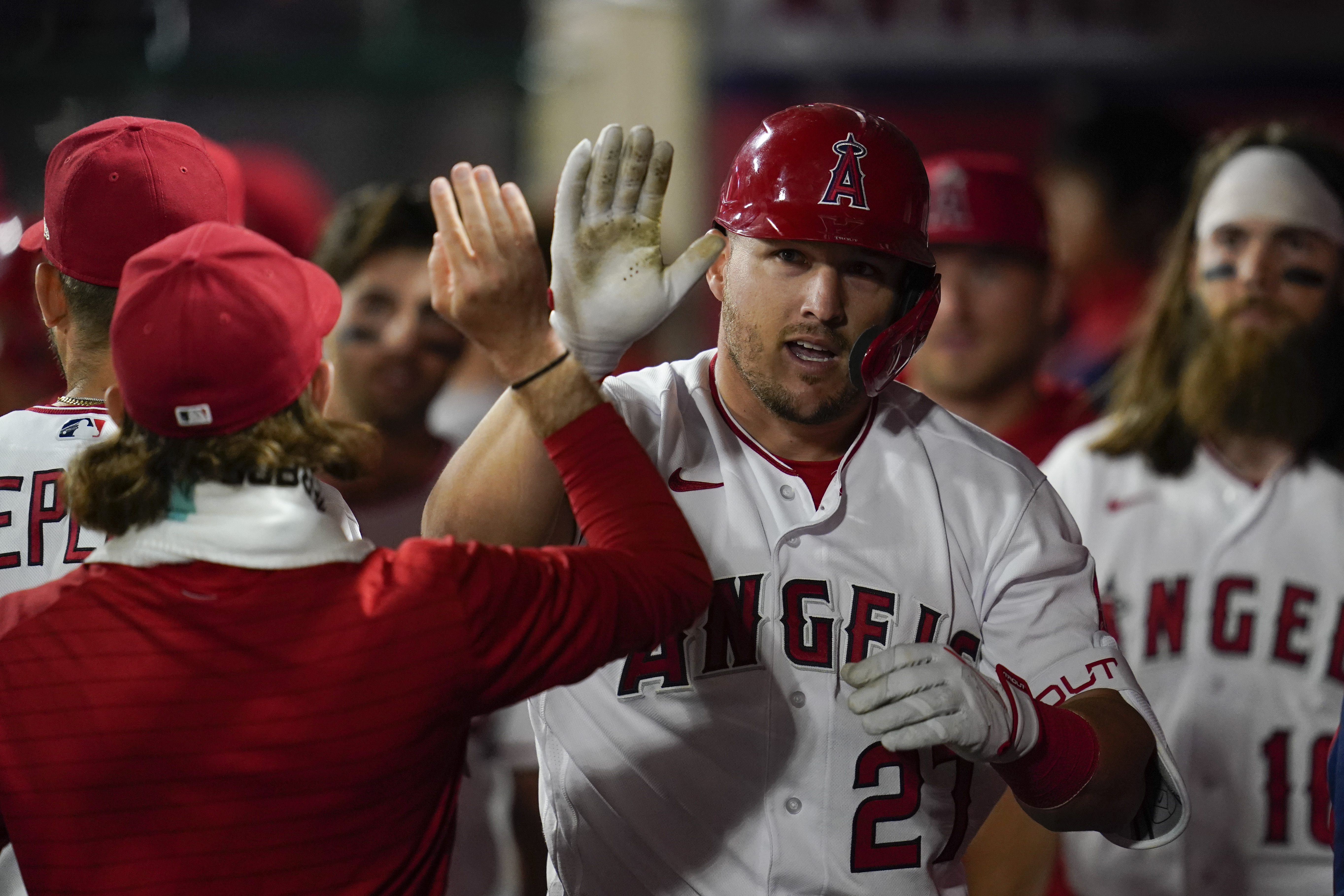 Los Angeles Angels center fielder Mike Trout (27) celebrates in the dugout after hitting a homerun during the seventh inning of a baseball game against the Houston Astros in Anaheim, Calif., Saturday, April 9, 2022. 